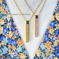 Two ayatul kursi necklaces with vertical pendants on a floral background, featuring the brand 'Siraat Al-Wilayah'.